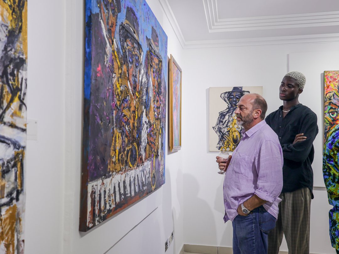 Guests standing before a large painting of saxophonists
