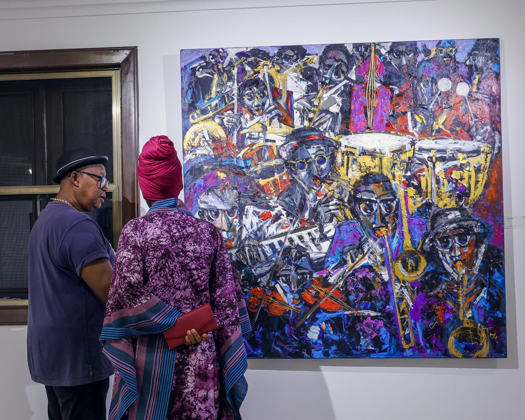 Two guests looking closely at a large painting of a jazz band